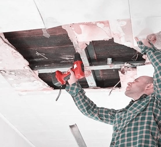 worker fixing ceiling metal frame with screwdriver